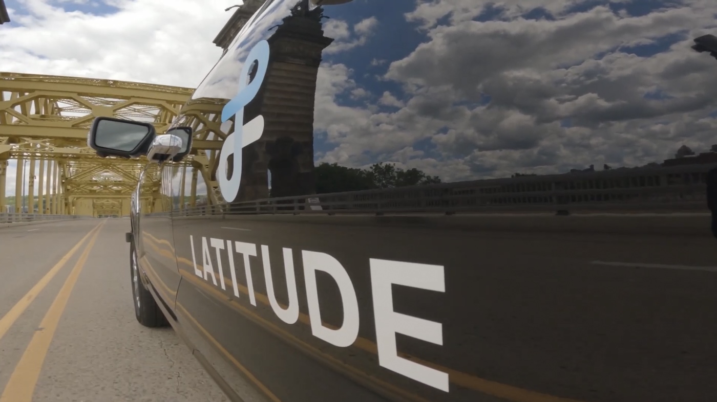 External shot of a Latitude vehicle in the city of bridges